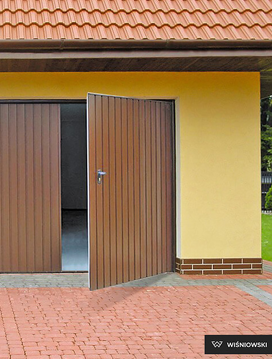 zdjęcie przedstawiające budynek gospodarczy z bramą rozwierną koloru brązowego, której producentem jest firma wiśniowski