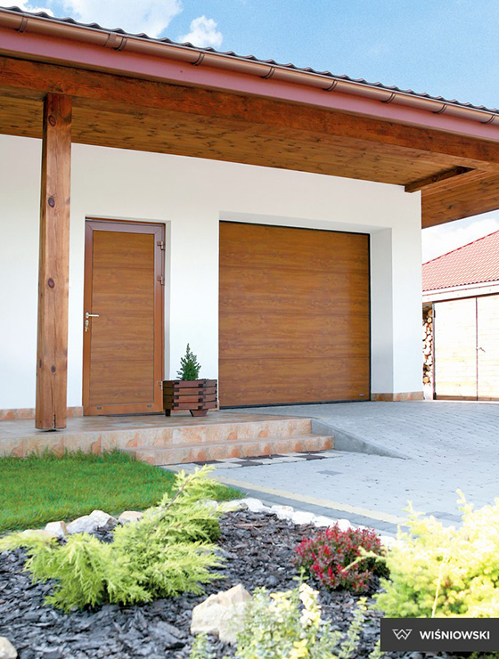 zdjęcie przedstawiające dom parterowy z bramą garażową segmentową oraz drzwiami garażowymi od firmy wiśniowski