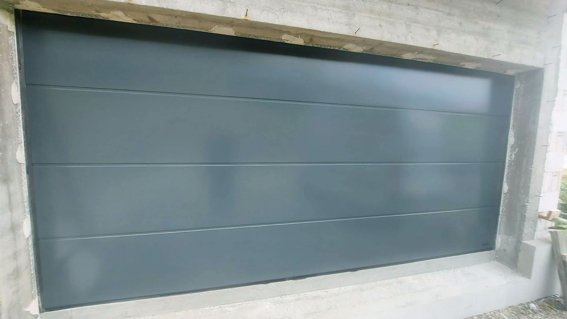 Zdjęcie przedstawiające bramę segmentową koloru grafitowego, którą zamontowała firma Monolit z Limanowej.