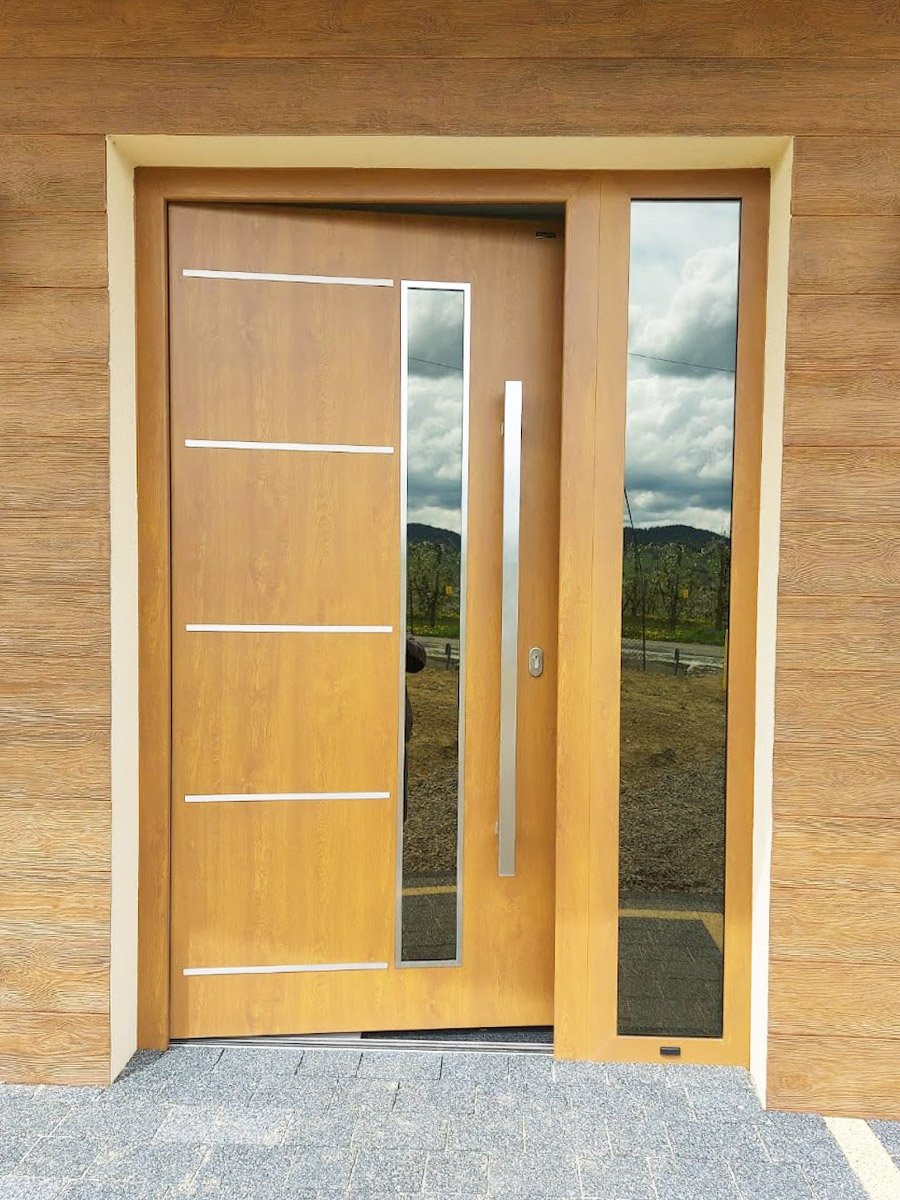 Zdjęcie przedstawiające drzwi wejściowe drewnopodobne jasne. Montaż wykonała firma Monolit Spółka Jawna Zawada.