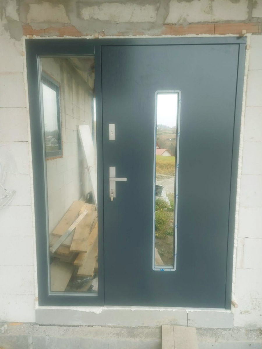 Zdjęcie przedstawiające drzwi wejściowe koloru grafitowego. Montaż wykonała firma Monolit Spółka Jawna Zawada.