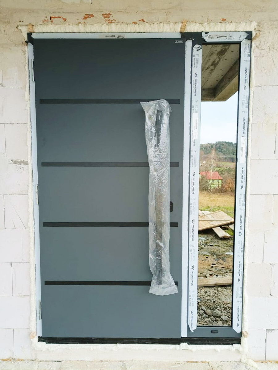 Zdjęcie przedstawiające drzwi wejściowe koloru grafitowego. Montaż wykonała firma Monolit Spółka Jawna Zawada.