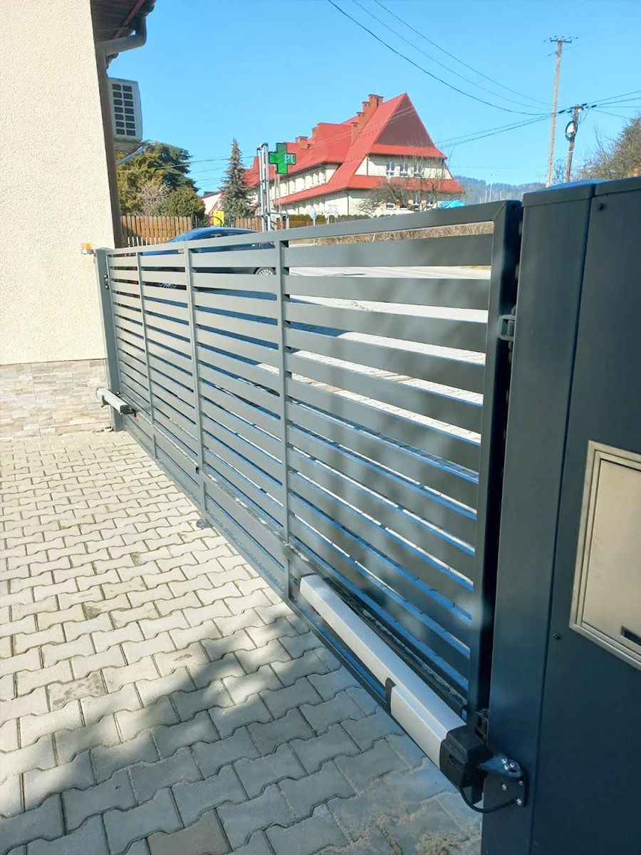 Zdjęcie przedstawiające bramę przesuwną z napędem koloru grafitowego. Montaż wykonała firma Monolit Spółka Jawna Zawada.