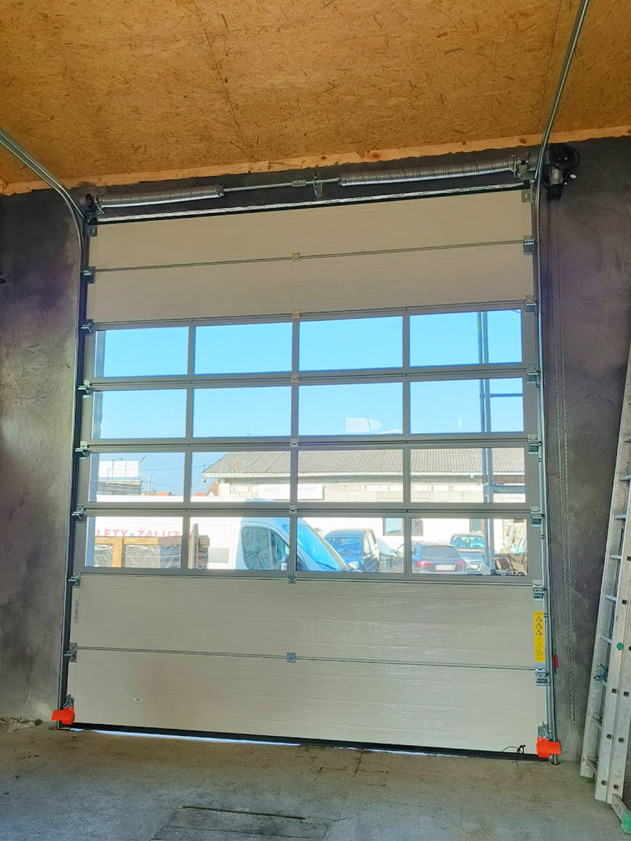 Zdjęcie przedstawiające wnętrze garażu z bramą segmentową z oknami. Montaż wykonała firma Monolit Spółka Jawna Zawada.